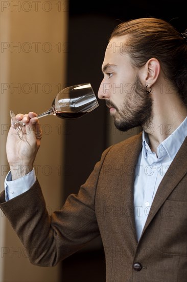 Young man smelling wine in glass at tasting