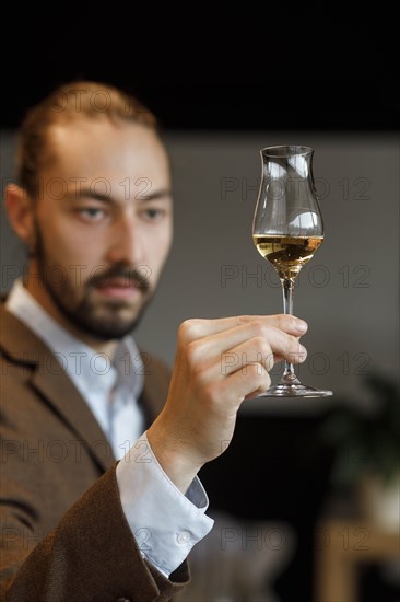 Young man examining glass of wine