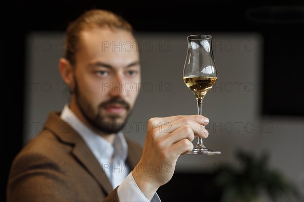 Young man examining glass of wine