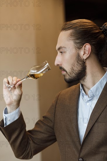 Young man smelling wine in glass at tasting