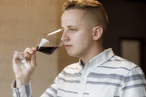 Young man smelling wine in glass at tasting