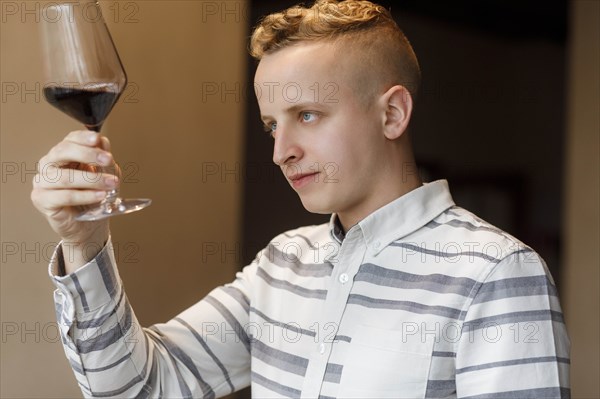 Young man examining glass of wine