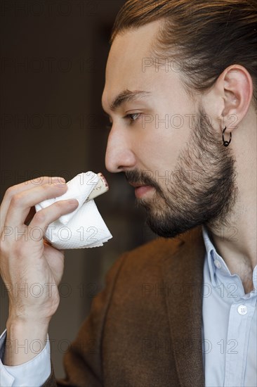 Young man smelling wine on cork at tasting
