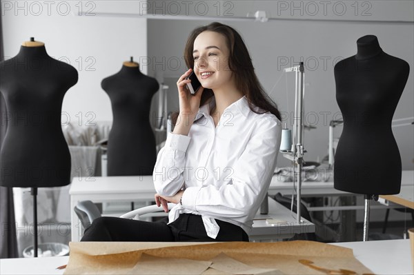 Fashion designer talking on smartphone in studio