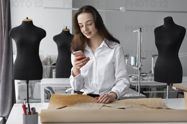 Fashion designer using smartphone in studio