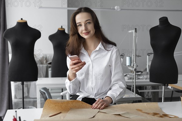 Fashion designer using smartphone in studio