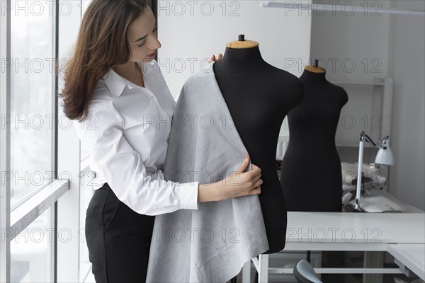 Fashion designer working with dressmaker's model in studio