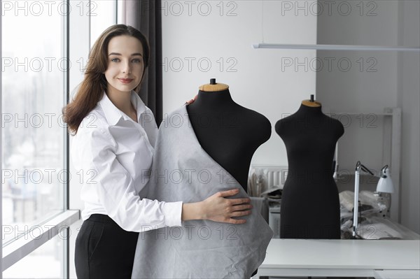 Fashion designer working with dressmaker's model in studio