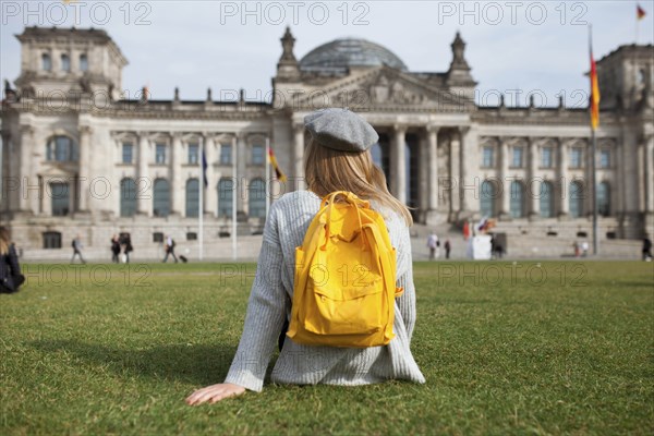 Young woman sitting in park by Reichstag in Berlin, Germany