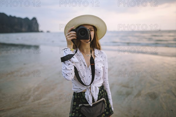 Young woman photographing on beach in Krabi, Thailand