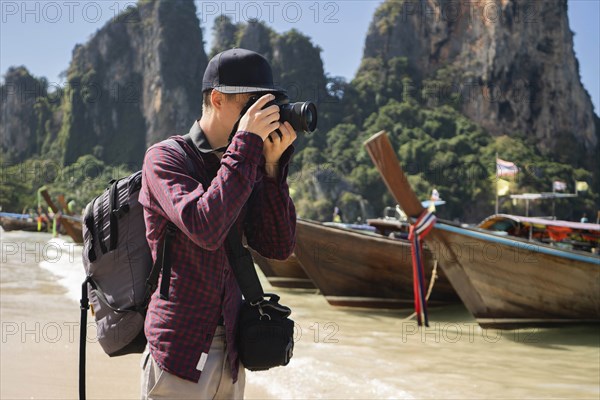 Young man photographing on beach in Krabi, Thailand