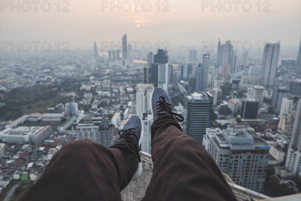 Legs of young man and cityscape of Bangkok, Thailand