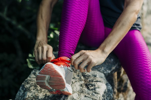 Woman tying her shoelaces on rock