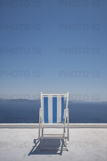 Striped deck chair on balcony by sea in Santorini, Greece