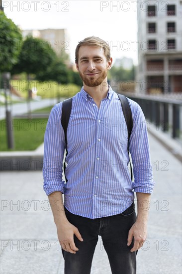 Man wearing striped shirt and backpack in city