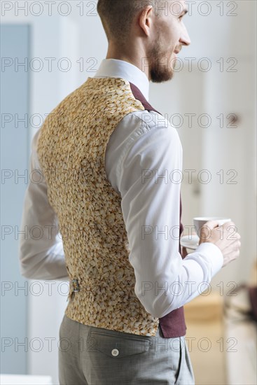 Man wearing patterned waistcoat holding tea cup