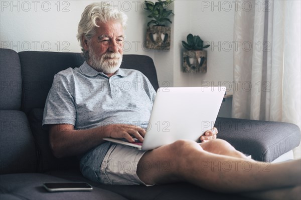 Senior man using laptop on sofa