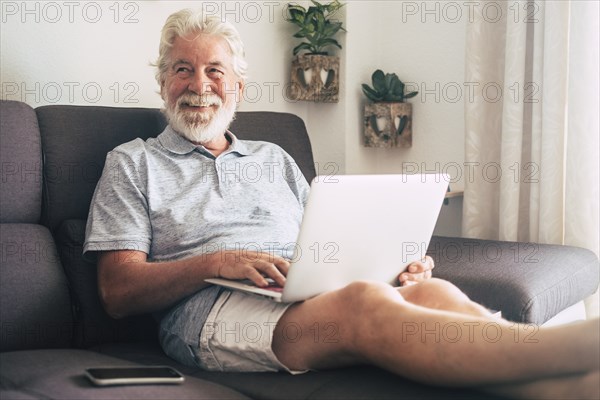 Smiling senior man using laptop on sofa