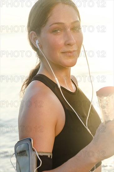 Woman wearing headphones holding water bottle