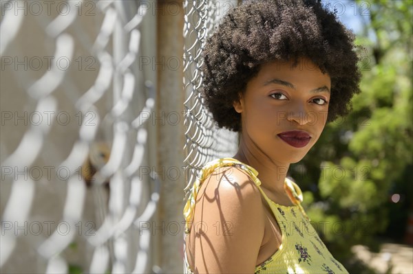 Portrait of young woman by wire fence