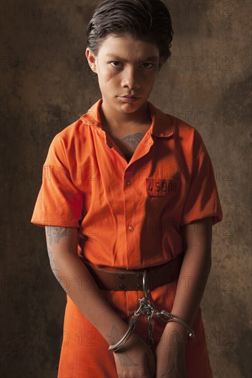 Boy in prisoner jumpsuit and handcuffs