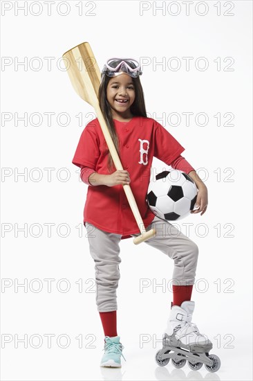 Girl dressed in baseball uniform holding sports equipment