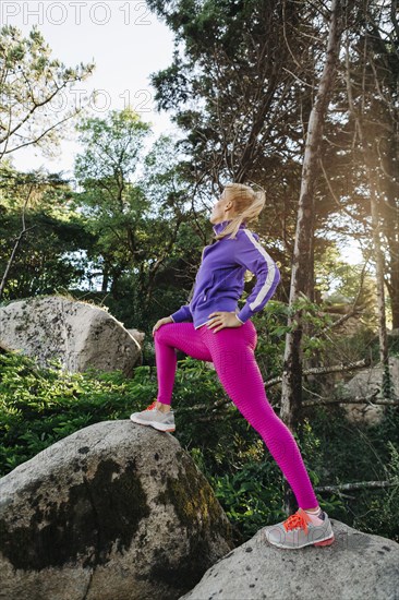 Woman wearing sportswear on rocks in forest