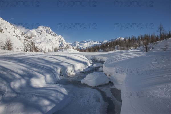 Frozen river in snow covered mountainous landscape in Alpe Devero, Italy