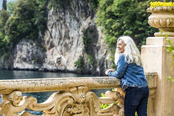 Woman leaning on balustrade at Villa del Balbianello by Lake Como, Italy