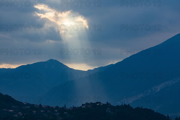 Sunbeams through clouds over mountains in Lombardy, Italy