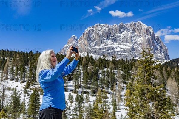 Woman taking photograph with smart phone by mountain in Dolomites, Italy