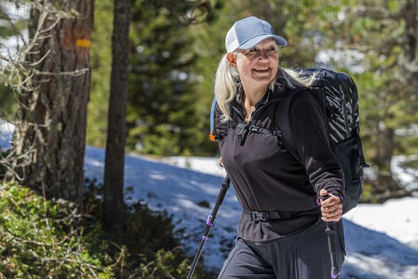 Mature woman hiking by trees on Munkel Trail in Val di Funes, Italy