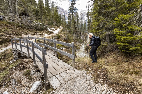 Woman hiking by footbridge on Giau Pass in Belluno, Italy