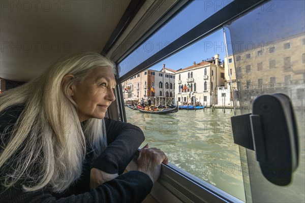 Woman looking out of boat window on Grand Canal, Venice, Italy