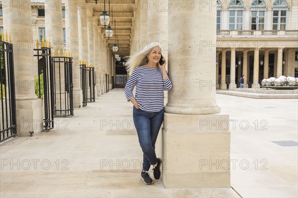 Woman on phone by columns of Palais-Royal in Paris, France