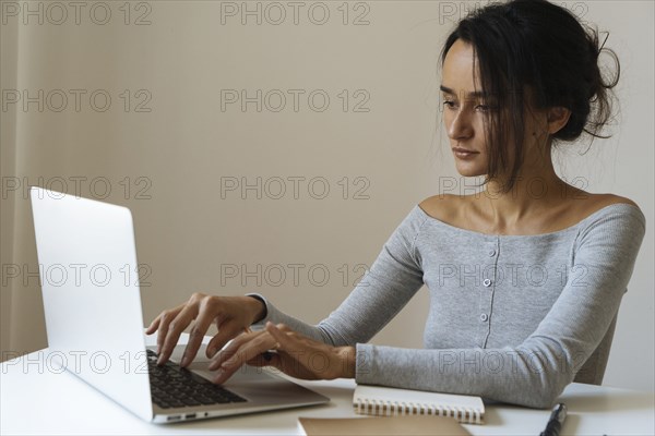 Woman using laptop with note pads