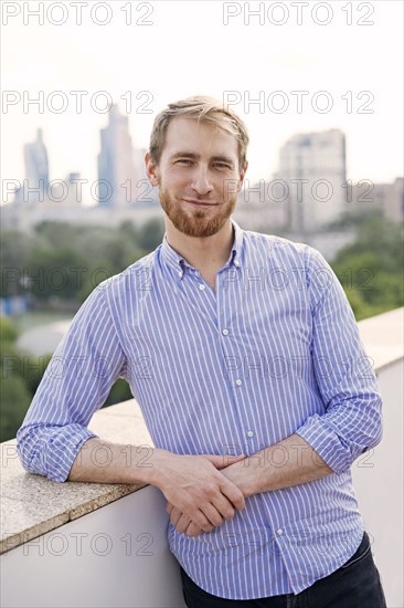 Man wearing striped shirt leaning on wall in city