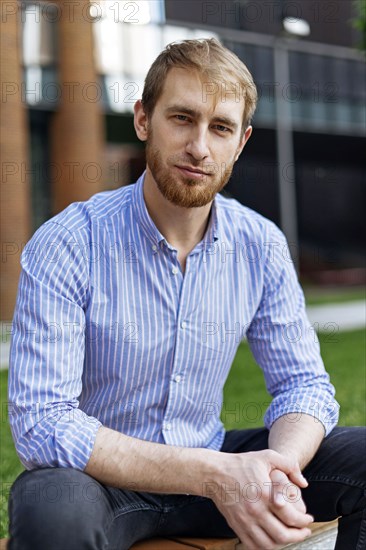 Man wearing striped shirt sitting on bench