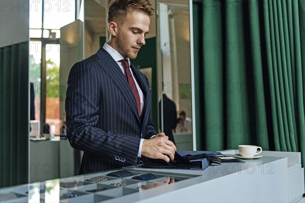 Shop assistant wearing pinstripe suit holding swatches