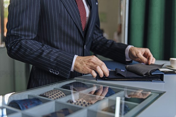 Shop assistant wearing pinstripe suit holding swatches