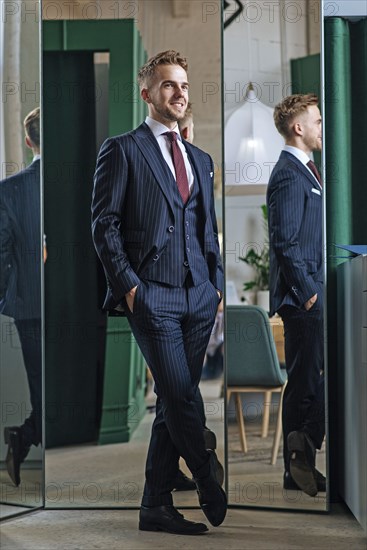 Smiling man wearing pinstripe suit by mirrors