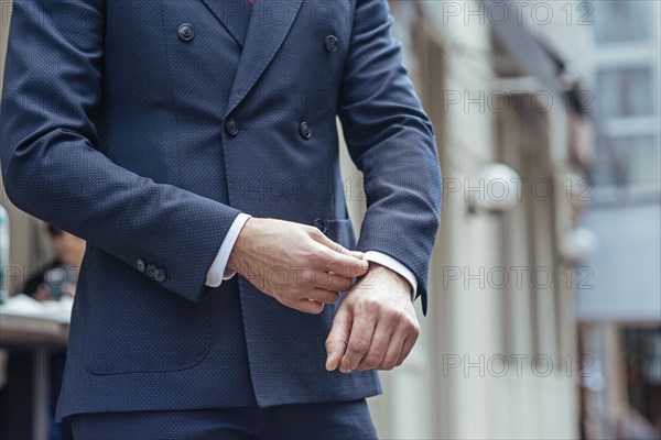 Man wearing double-breasted suit adjusting his cuff