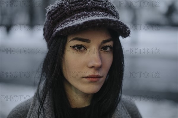 Portrait of young woman wearing woolly hat and eyeliner