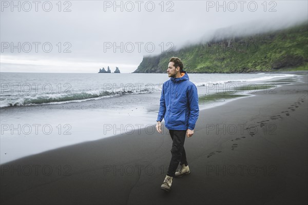 Man walking on beach in Vik, Iceland