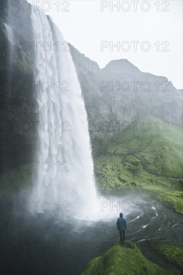 Man standing by Seljalandsfoss waterfall in Iceland