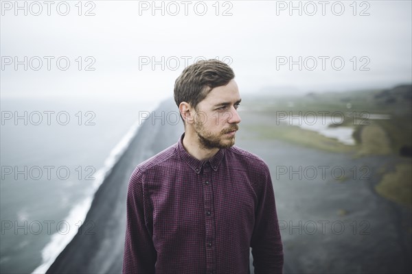 Bearded man above beach in Vik, Iceland