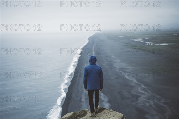 Man wearing blue coat above beach in Vik, Iceland