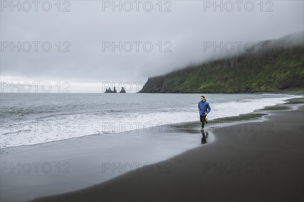 Man jogging on beach in Vik, Iceland