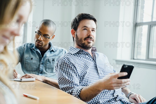 Man holding smart phone during meeting