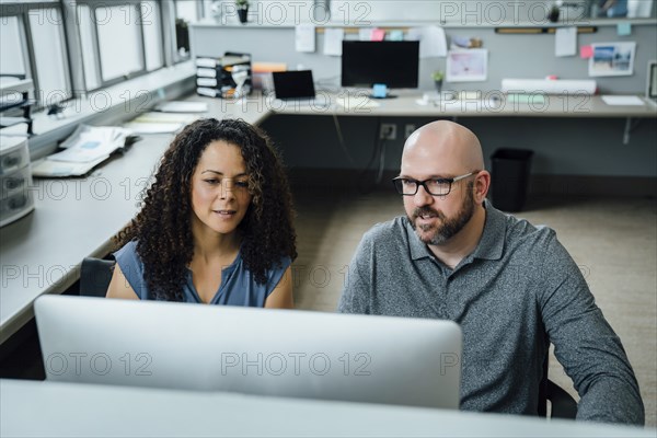 Coworkers using computer in office